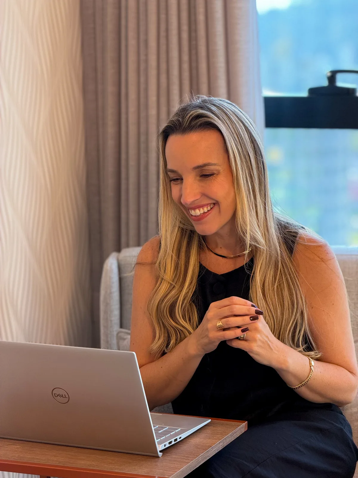 Ana Pamplona sorrindo durante um atendimento online pelo computador.