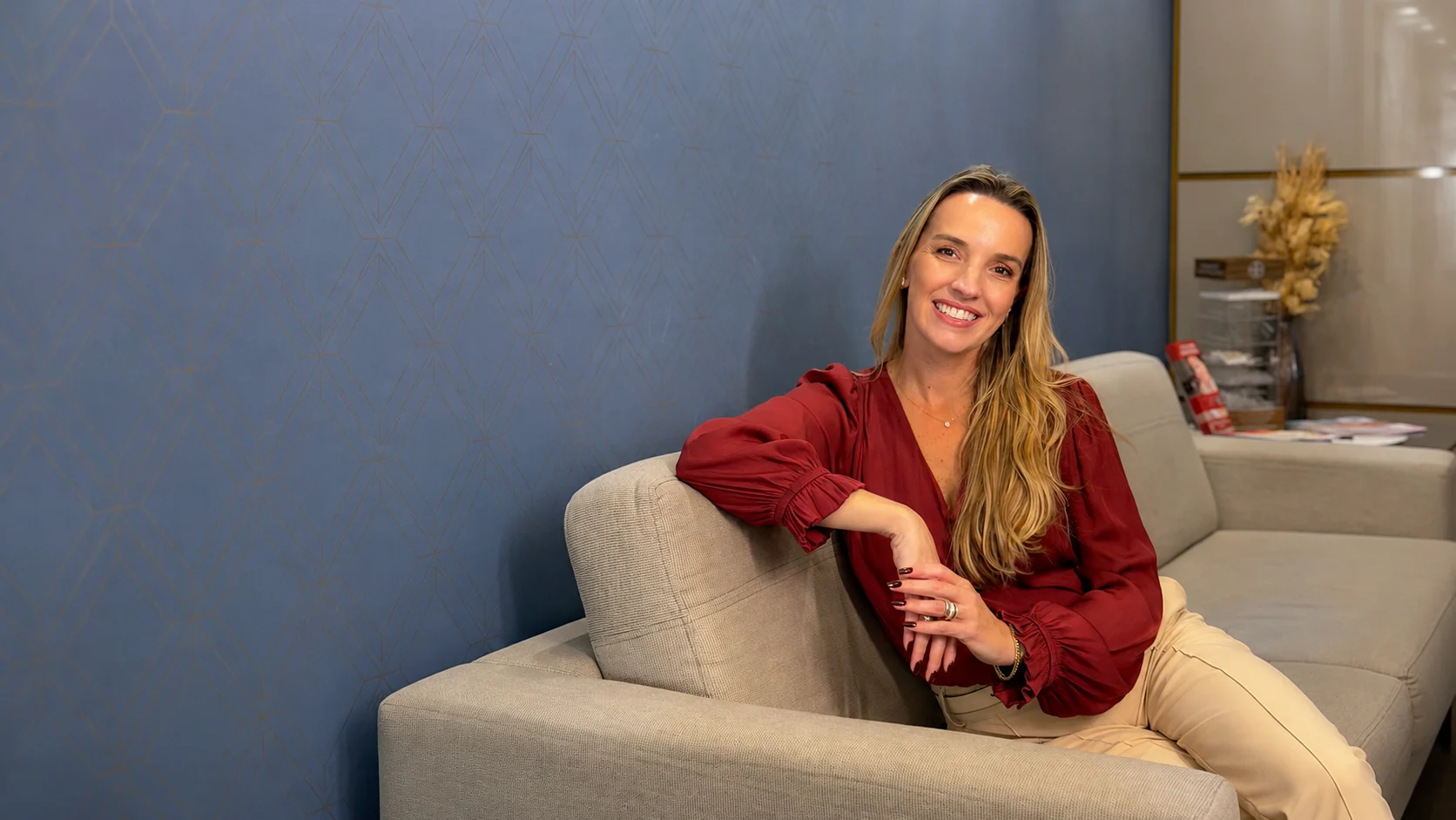 Ana Pamplona, psicóloga do Instituto Pulsar, sorrindo sentada no sofá da clínica.